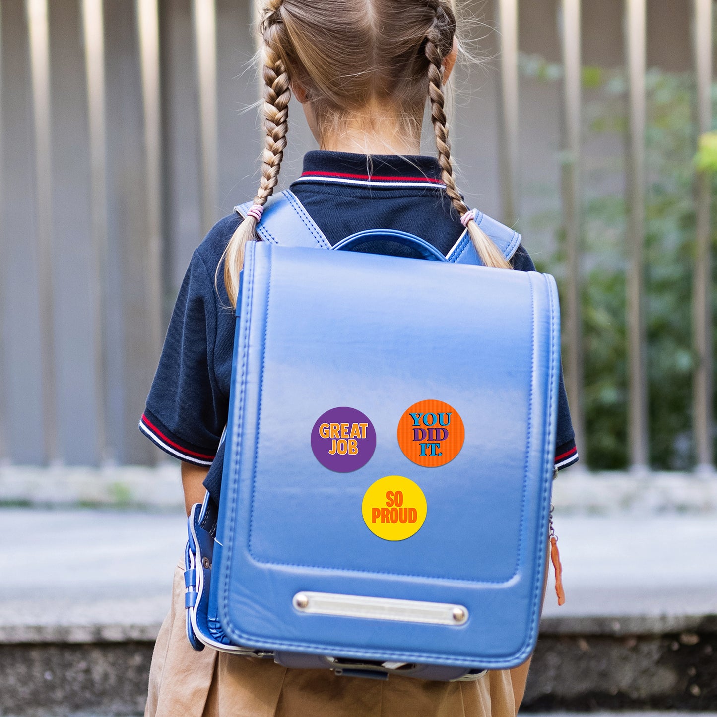 Child wearing a blue backpack with encouraging stickers outdoors