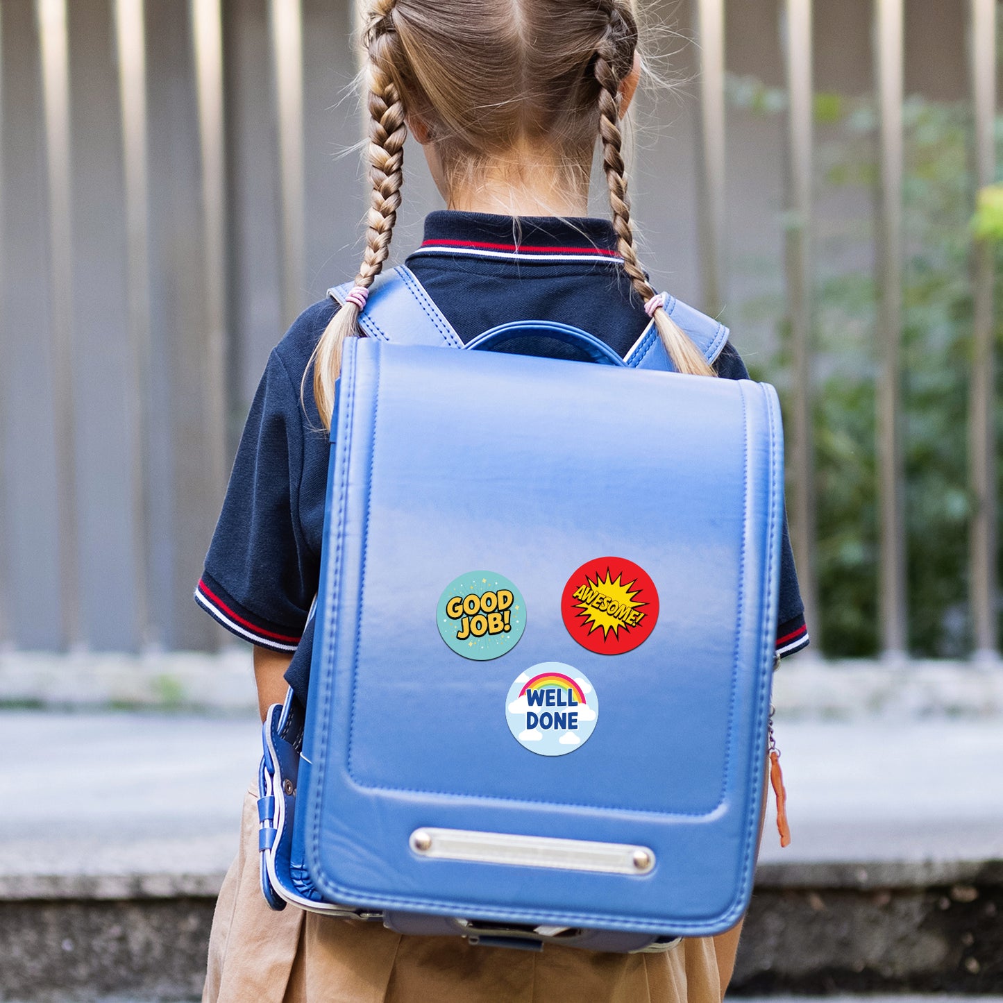 Child wearing a blue backpack with colorful Encouraging Sticker – Comic Reward Design stickers outdoors