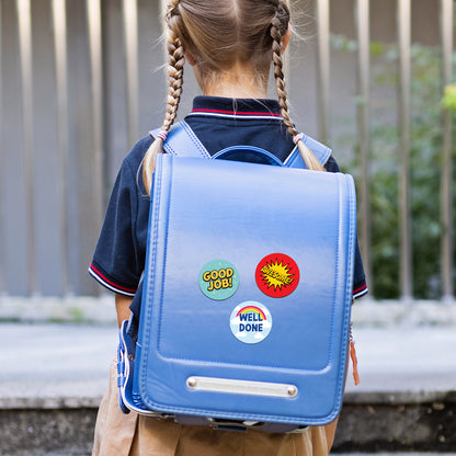 Child wearing a blue backpack with colorful Encouraging Sticker – Comic Reward Design stickers outdoors