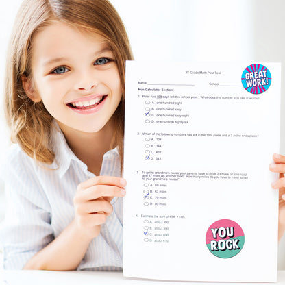 Child holding a math test with 'Great Work!' and 'You Rock!' Encouraging stickers
