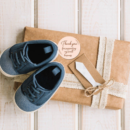 Blue baby shoes on a wrapped gift with a Thank You Sticker – Blush Script Design on card on a wooden surface
