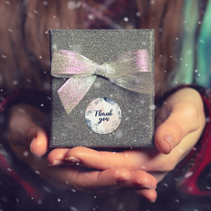 Person holding a glittery gift box with a bow and 'Thank you stickers' tag.