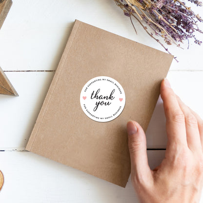 Brown paper package with a Thank You Sticker – Minimal Circle Design sticker on a white surface with lavender.